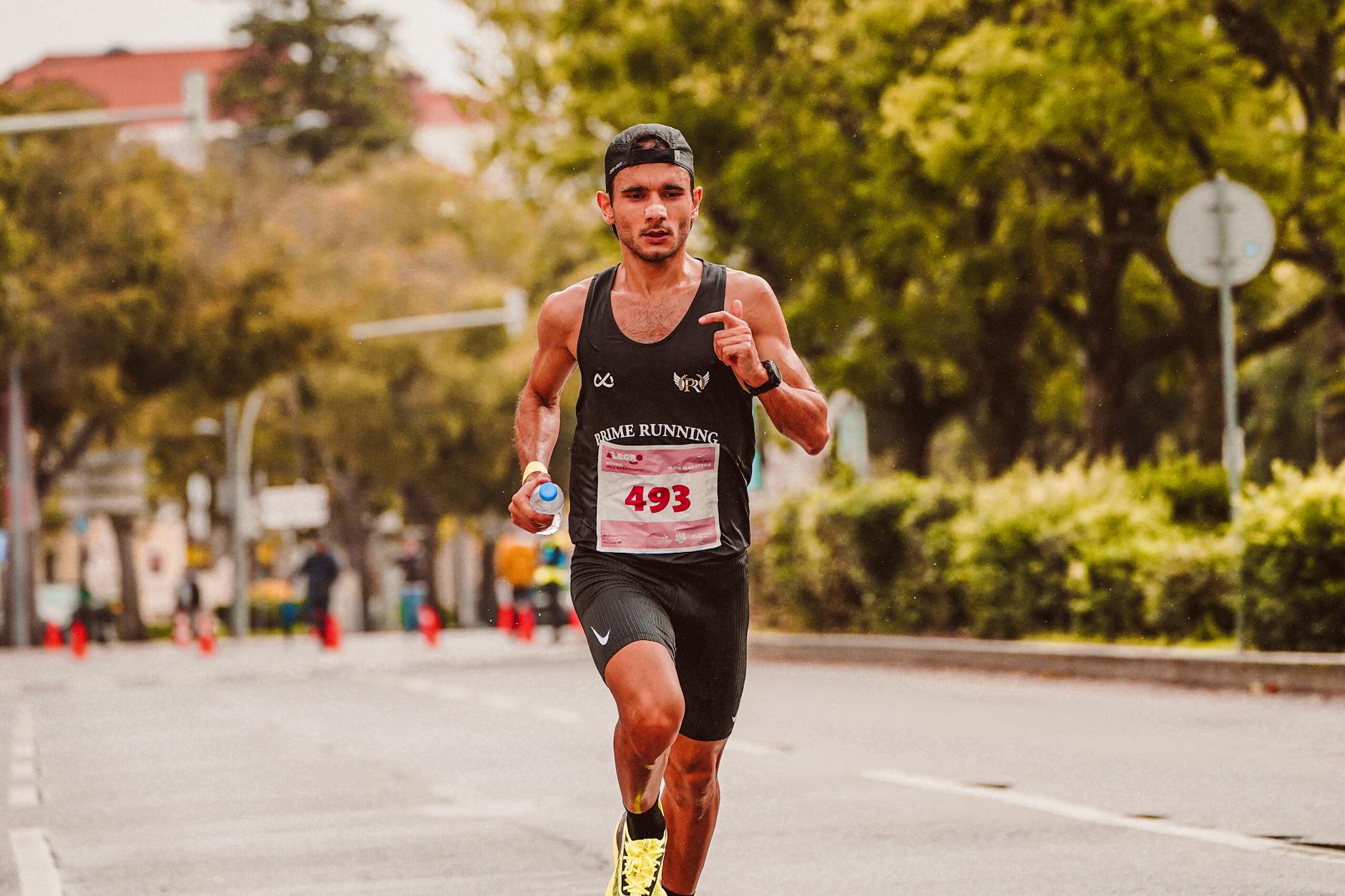 Mężczyzna biegnący w maratonie z butelką wody w dłoni